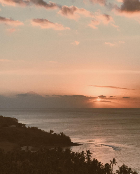 The sun sets over a tropical break, as seen from high on a bluff