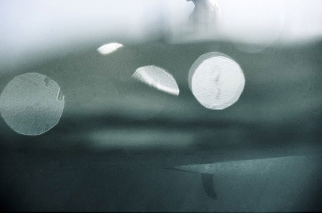 An abstract photo of a surfer sitting on a board, taken from underwater